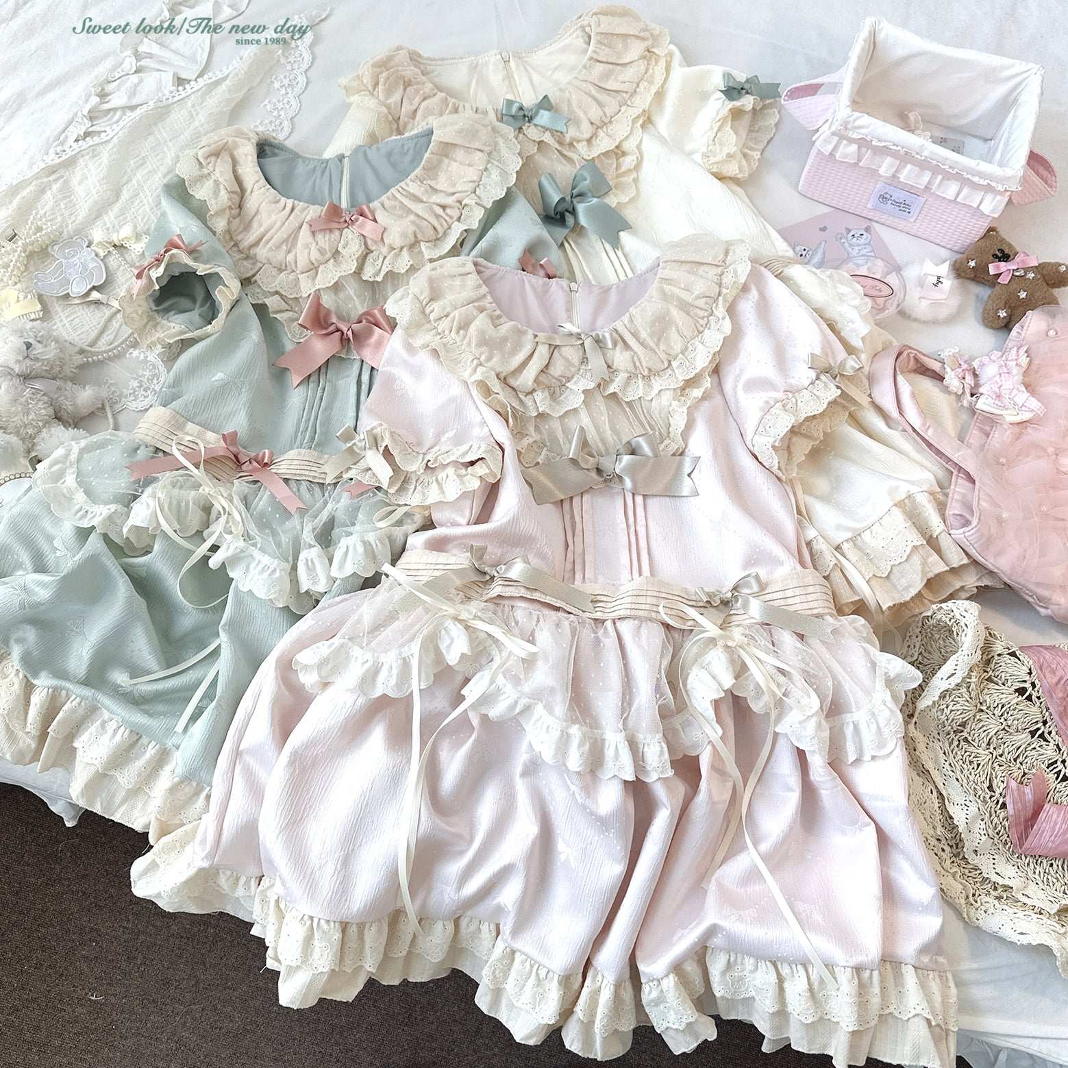 Collection of pastel-colored dresses with ruffles and bows on a white surface.