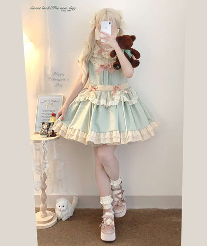 Person wearing a light green dress with ruffles, holding a teddy bear, in a room setting.