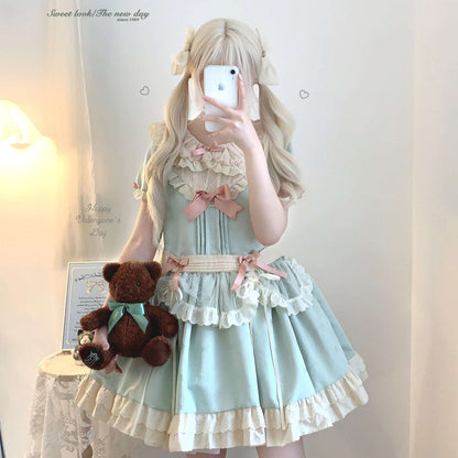 Person wearing a light blue dress with ruffles and pink bows, holding a teddy bear.