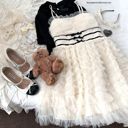 White dress with black accents, shoes, teddy bear, and accessories on a textured surface.