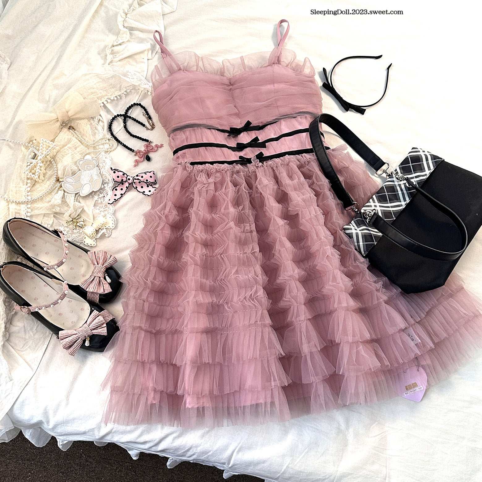Pink tiered dress with accessories on a white background