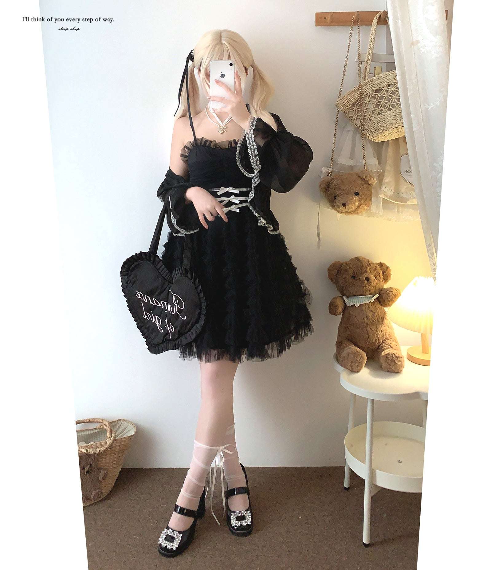 Person wearing a black outfit with a white background, holding a phone.