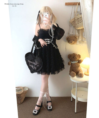 Person wearing a black outfit with a white background, holding a phone.