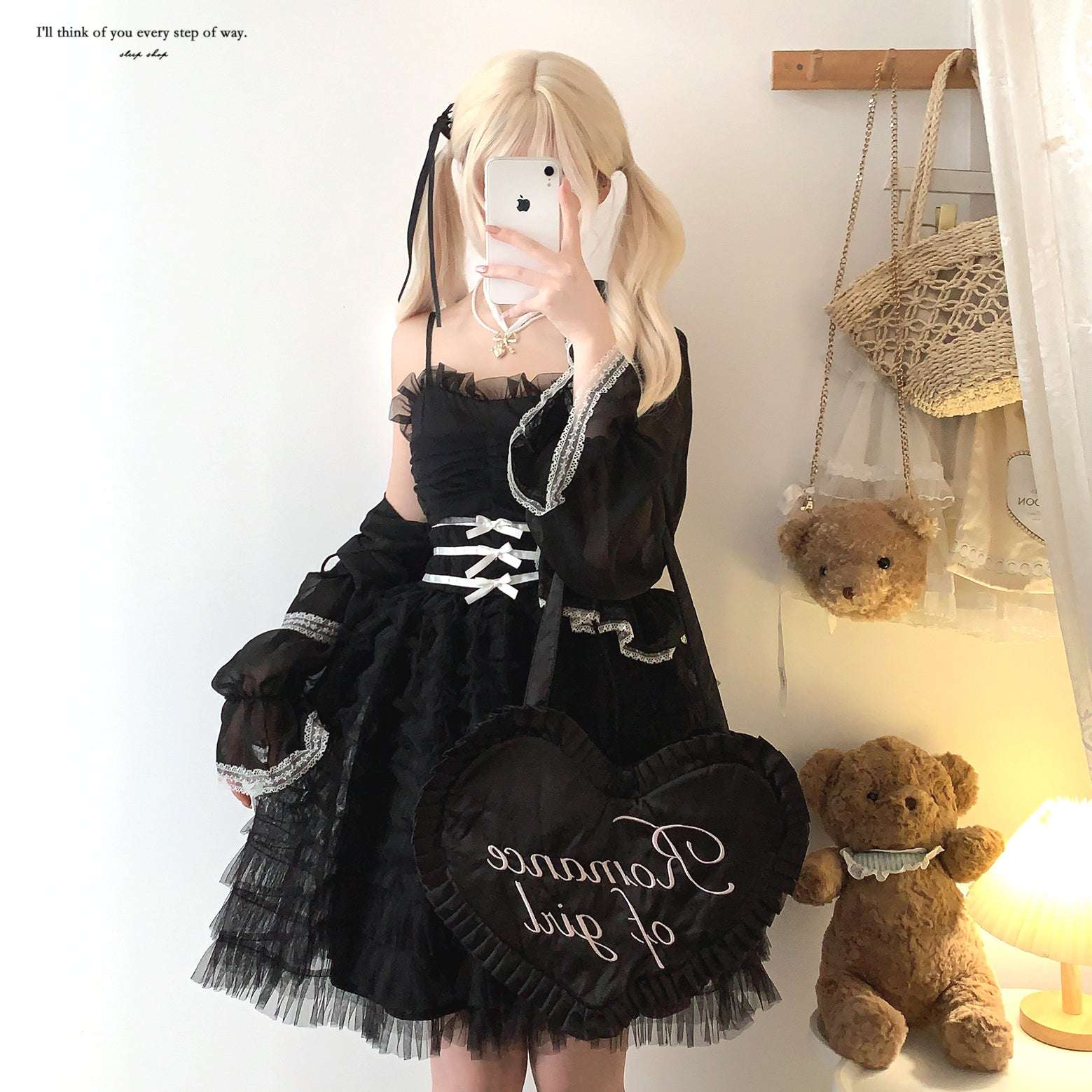 Person wearing a black lace dress with white text, standing next to teddy bears in a room.