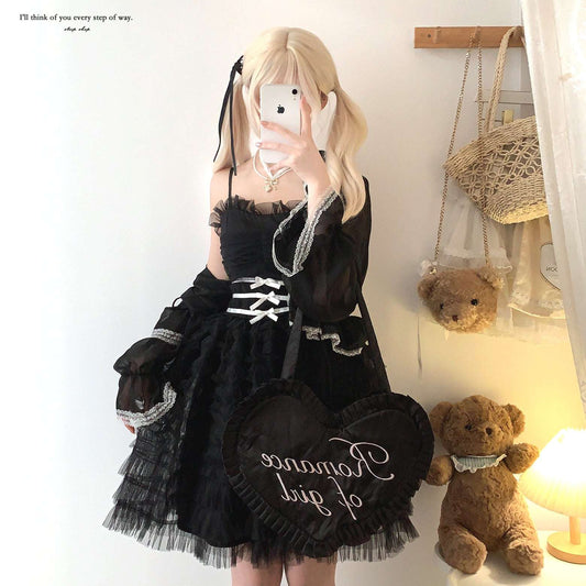 Person wearing a black lace dress with white text, standing next to teddy bears in a room.
