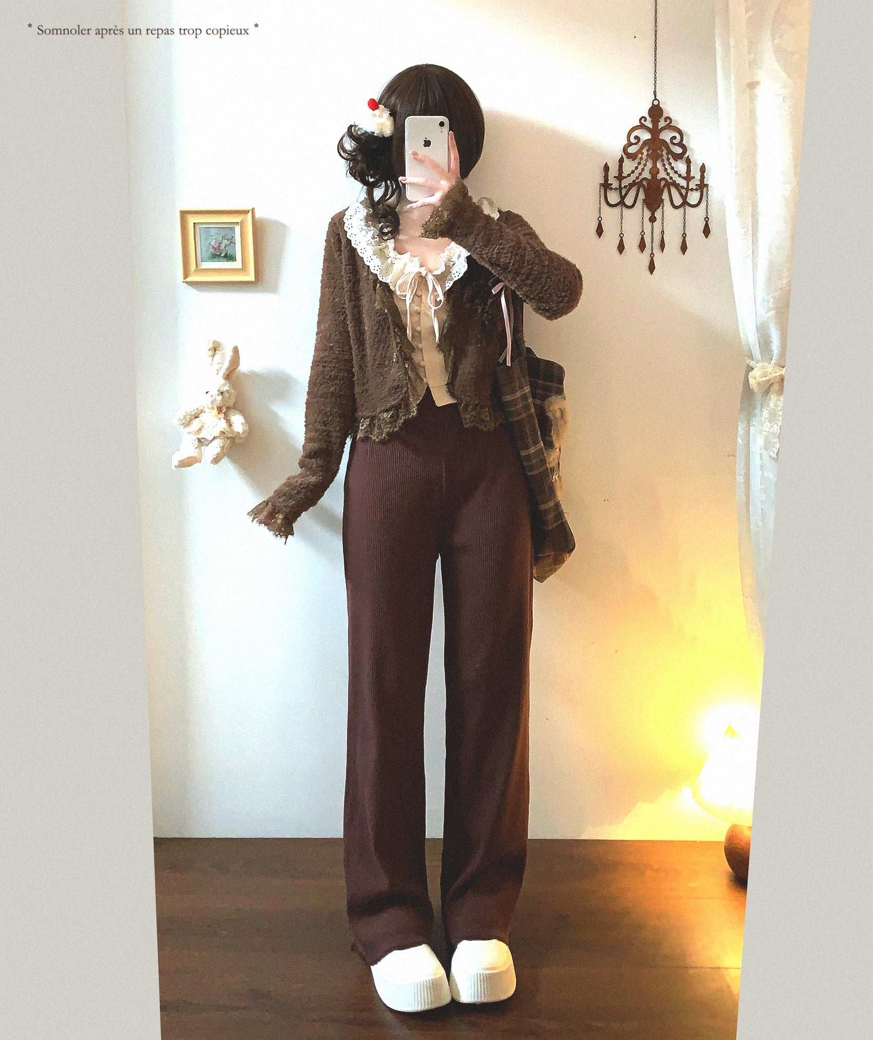 Person wearing a brown outfit with a scarf in a room with a chandelier and framed picture.