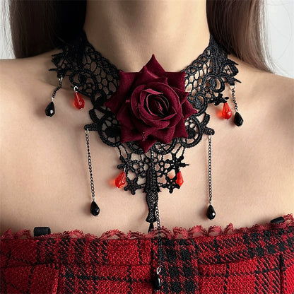 Black lace choker with a red rose and red teardrop pendants on a person wearing a red and black checkered top.