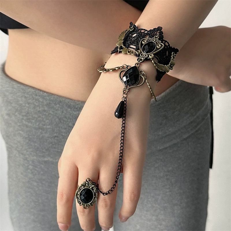 Black lace bracelet with chain and black gemstones on a wrist, with a matching ring on a finger.