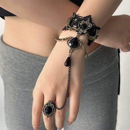 Black lace bracelet with chain and black gemstones on a wrist, with a matching ring on a finger.