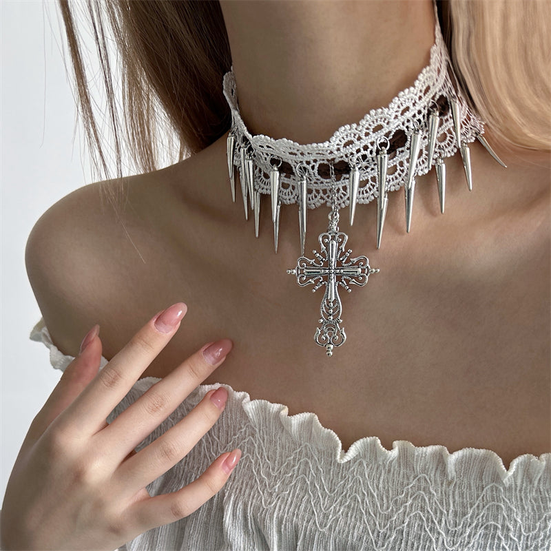 Person wearing a lace choker with spikes and a cross pendant on a plain background