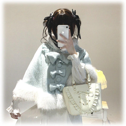 Person wearing a light blue vest with large bows and white fur trim, holding a phone.