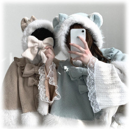 Two people wearing fluffy hooded outfits with large bows, one holding a phone.