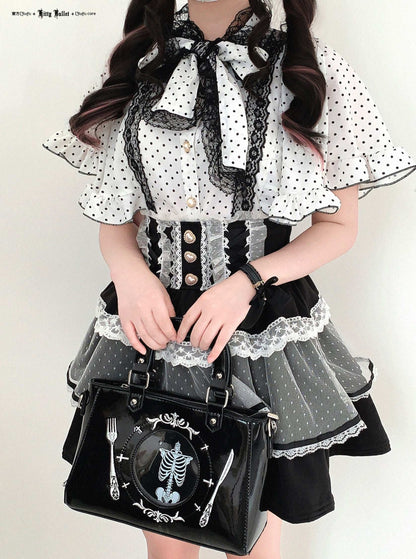 Person wearing a black and white polka dot dress with a skeleton design handbag.
