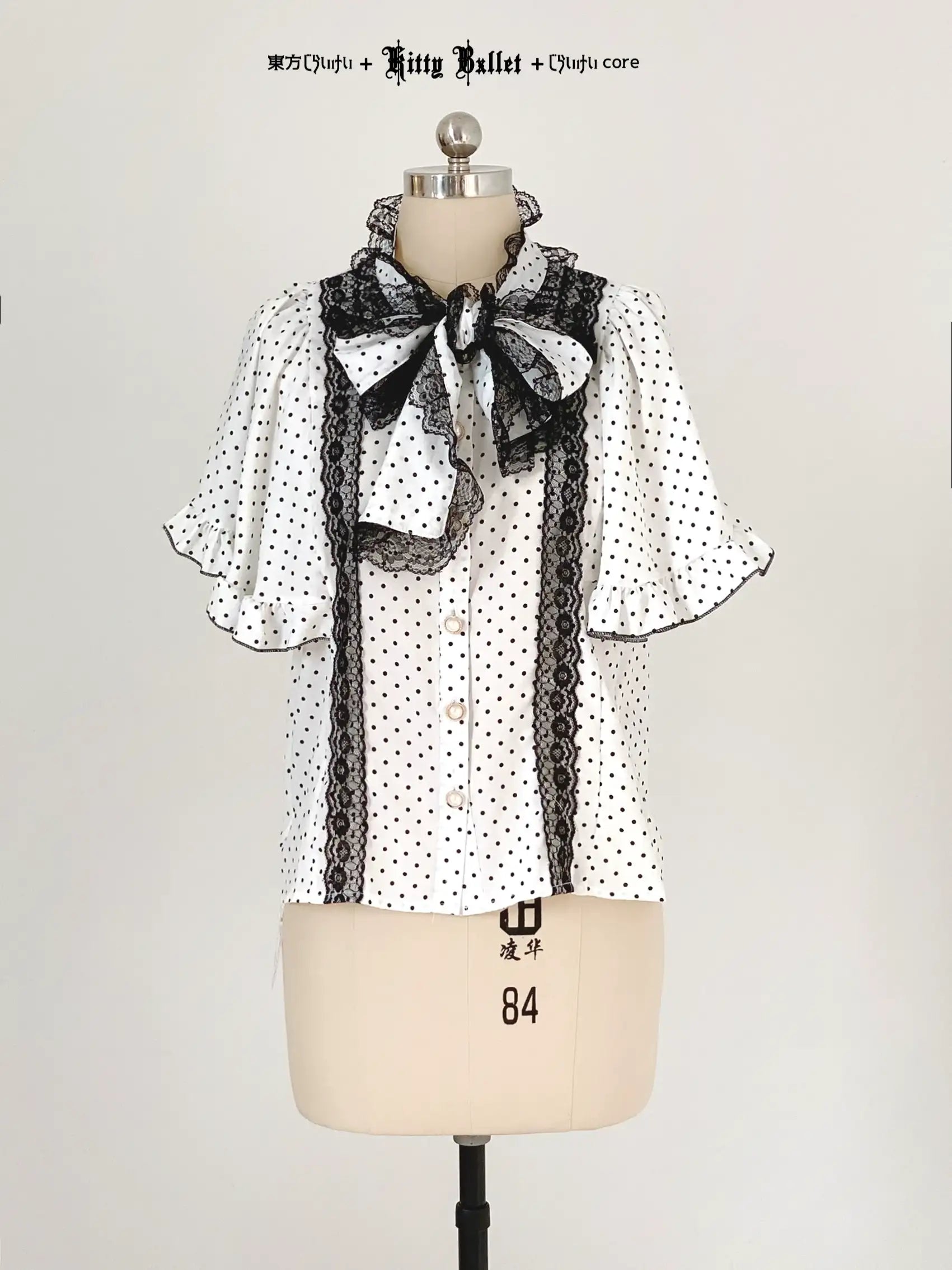 Polka dot blouse with black lace details on a mannequin against a plain background