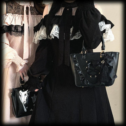 Person wearing a jirai kei styles black outfit with lace details holding a black handbag.