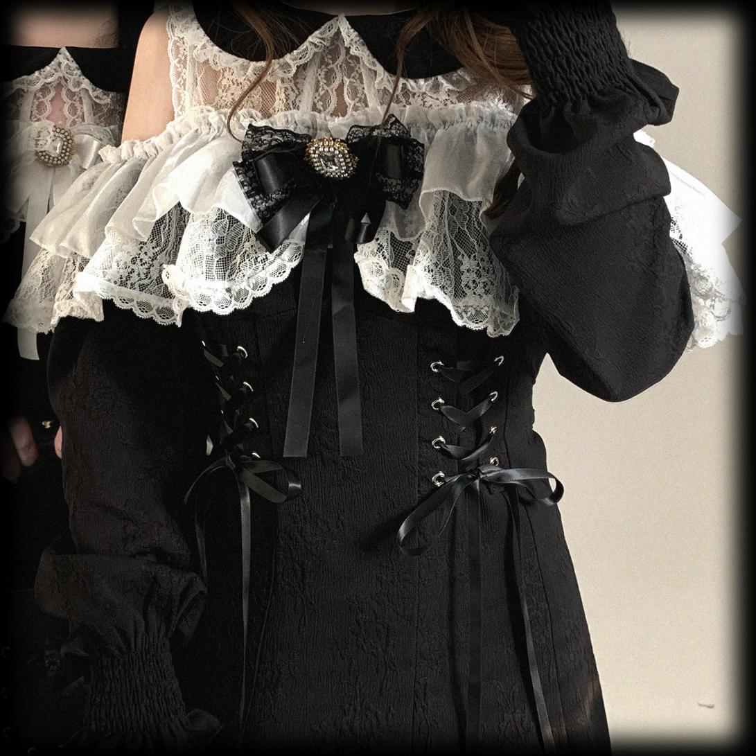 Black and white lace dress with black gloves and ribbons on a neutral background