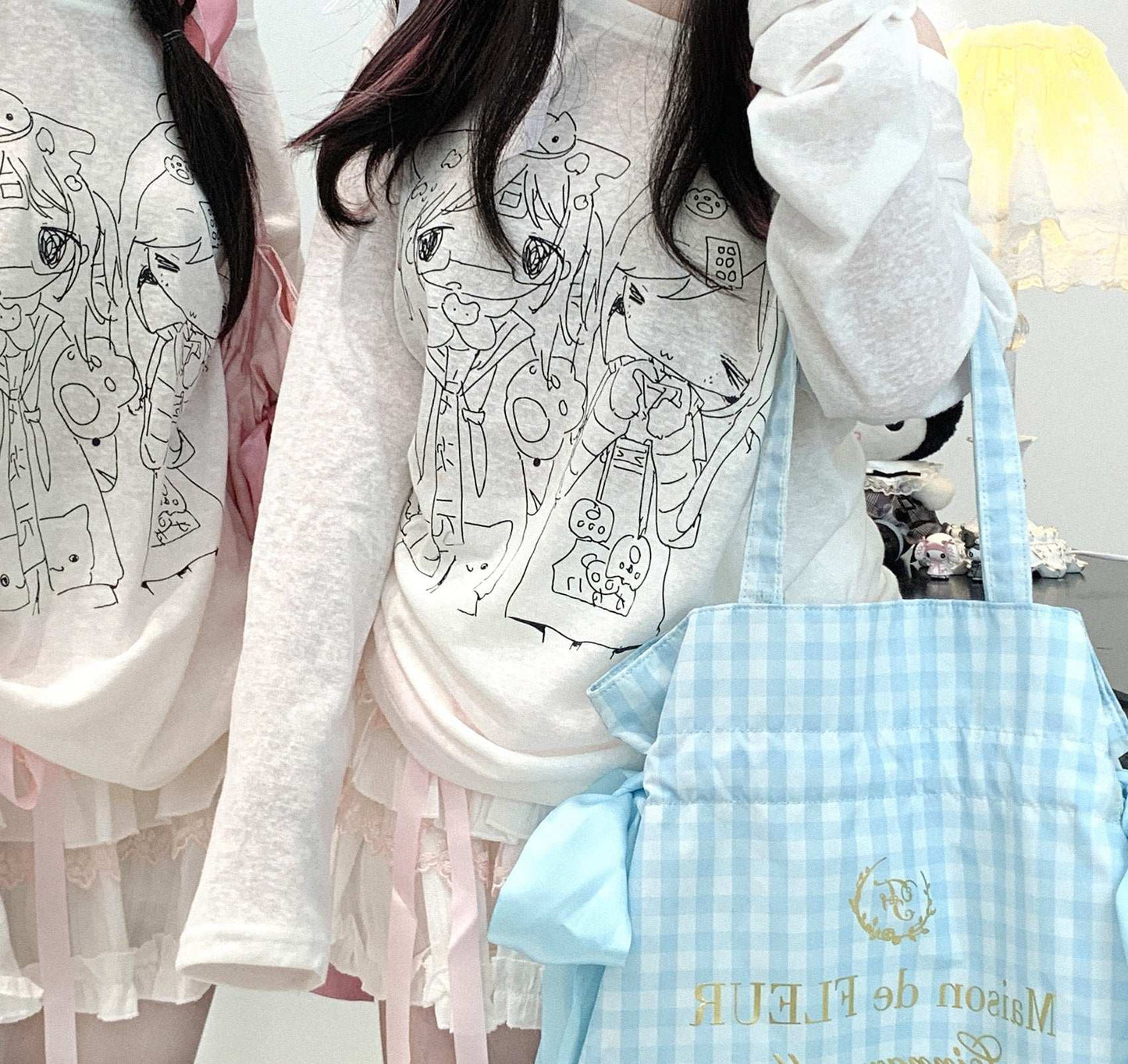 Two people wearing white shirt with black line art designs, one holding a blue checkered bag.