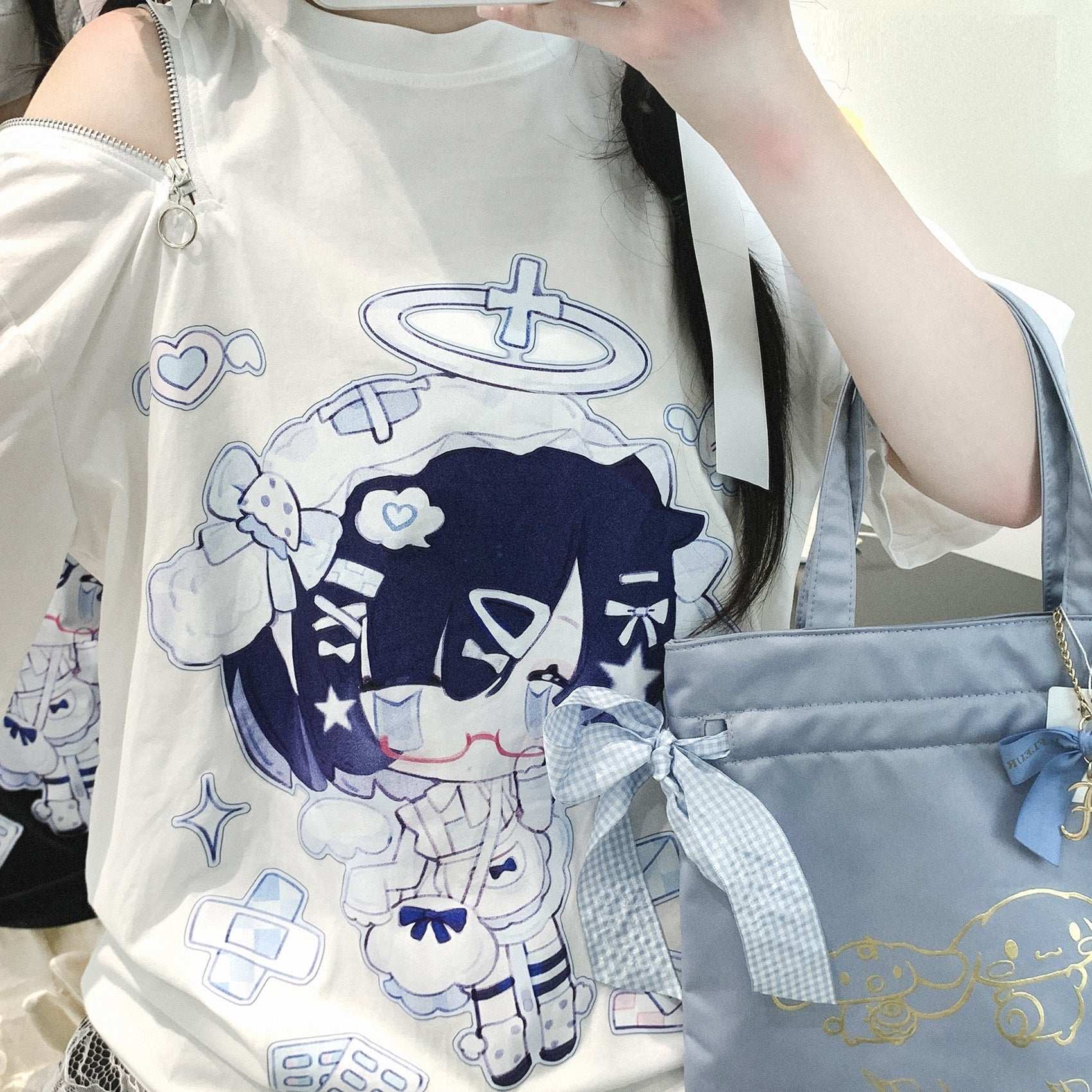Person wearing a white t-shirt with cartoon character design and holding a blue handbag.