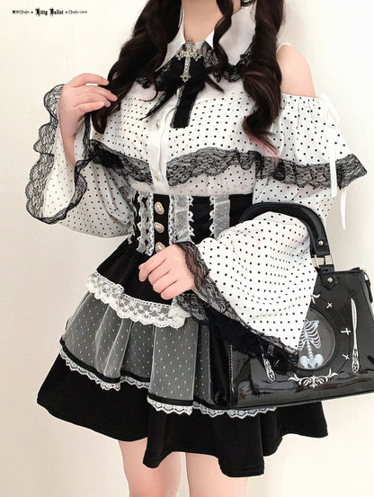 Person wearing a black and white polka dot dress with a matching handbag on a plain background