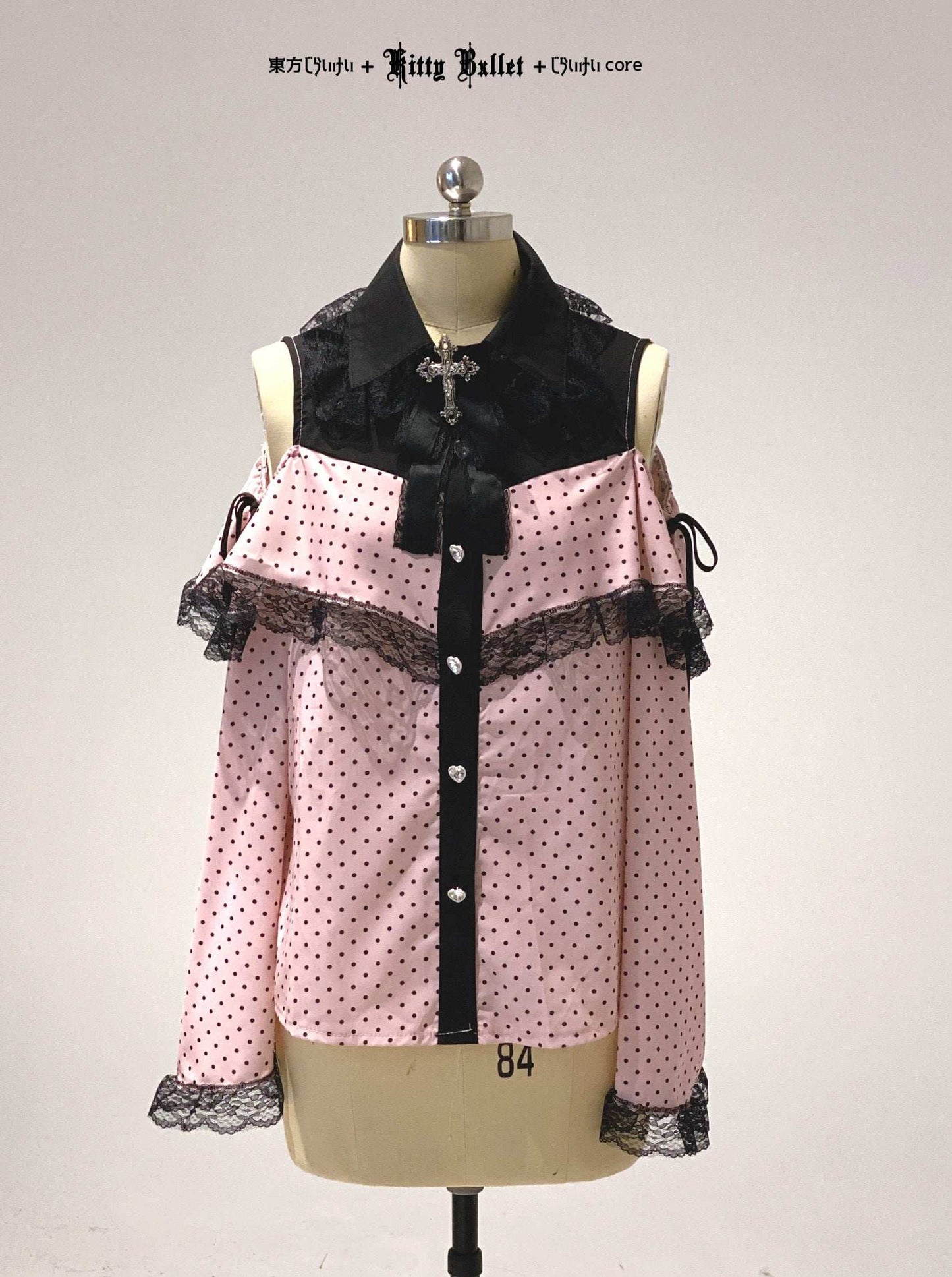Pink polka dot blouse with black accents on a mannequin against a white background