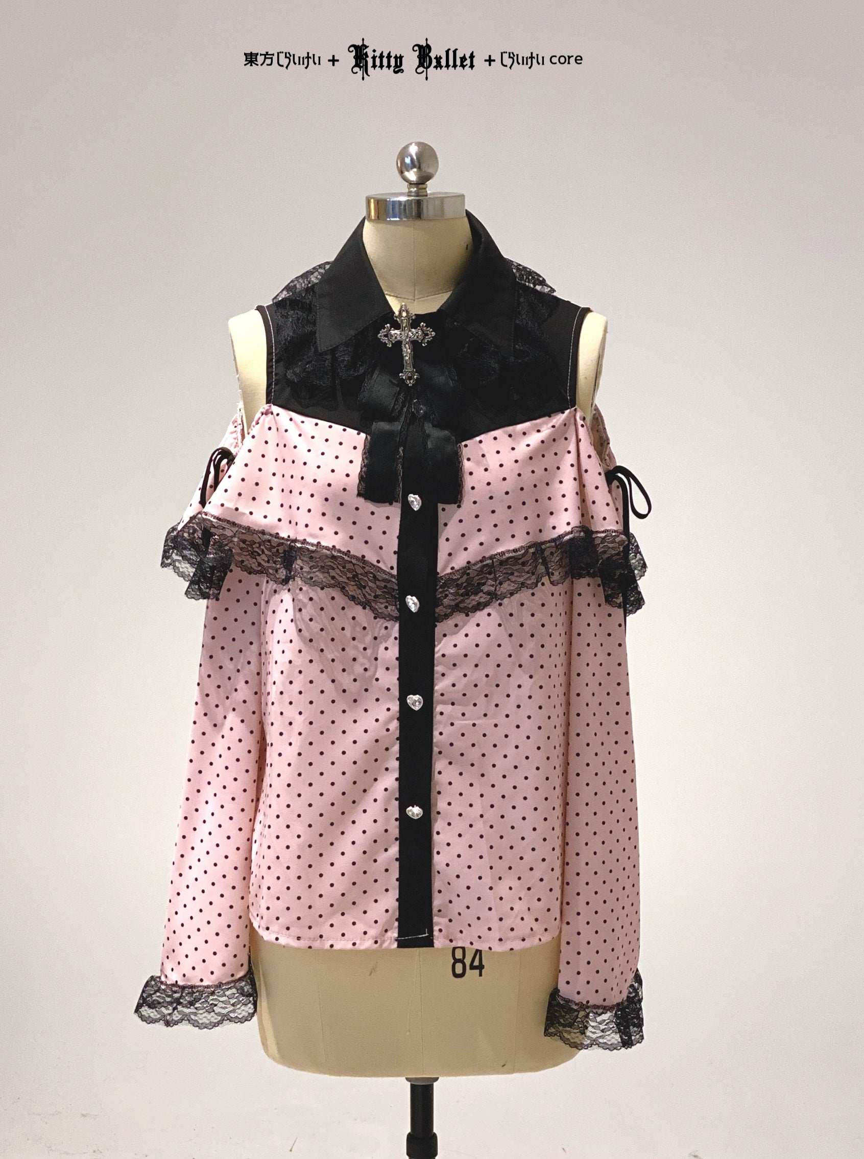 Pink polka dot blouse with black accents on a mannequin against a white background