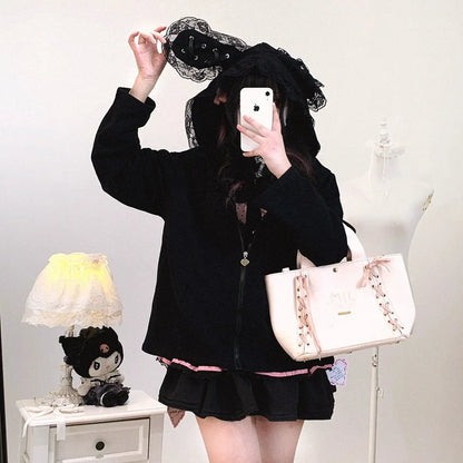 Person in black outfit with pink accents holding a white handbag, taking a mirror selfie.