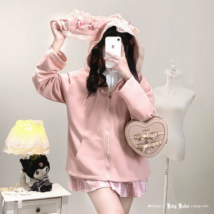 Person wearing a pink hoodie and skirt with a heart-shaped bag, taking a mirror selfie.