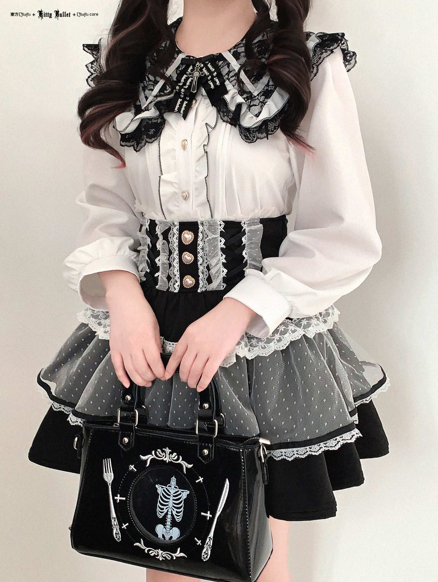 Person wearing a gothic Lolita outfit with a black handbag featuring skeleton and fork designs.