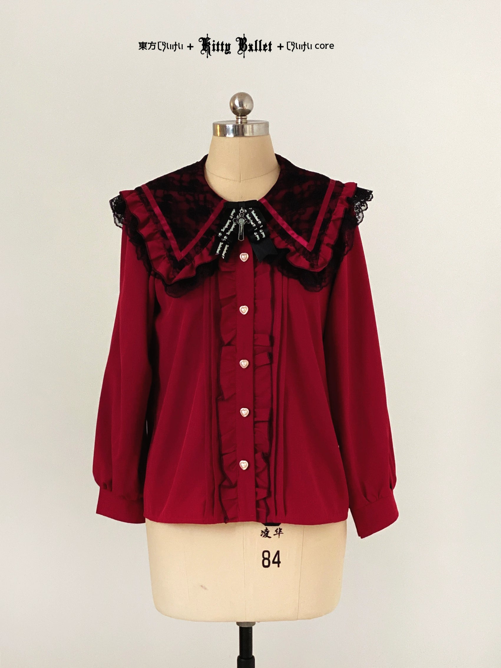 Red blouse with black ruffled collar on a mannequin against a plain background