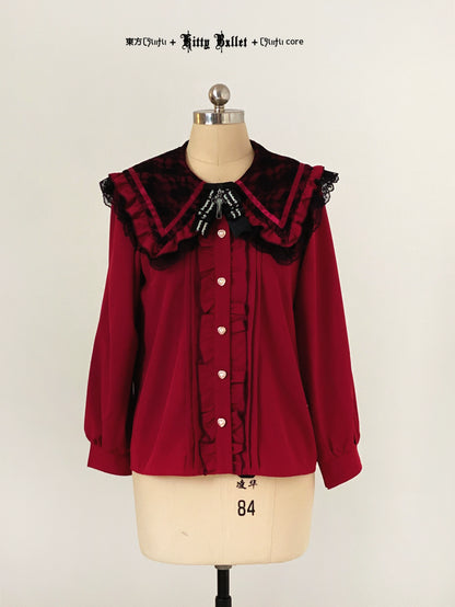 Red blouse with black ruffled collar on a mannequin against a plain background