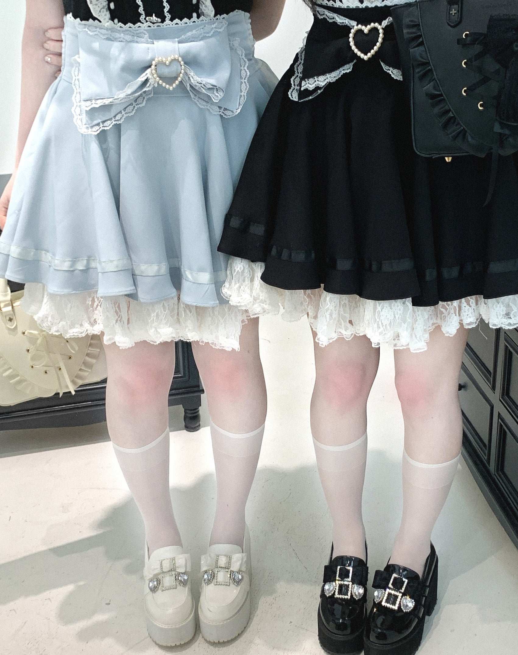 Two skirts, one light blue and one black, worn by models on a plain background.