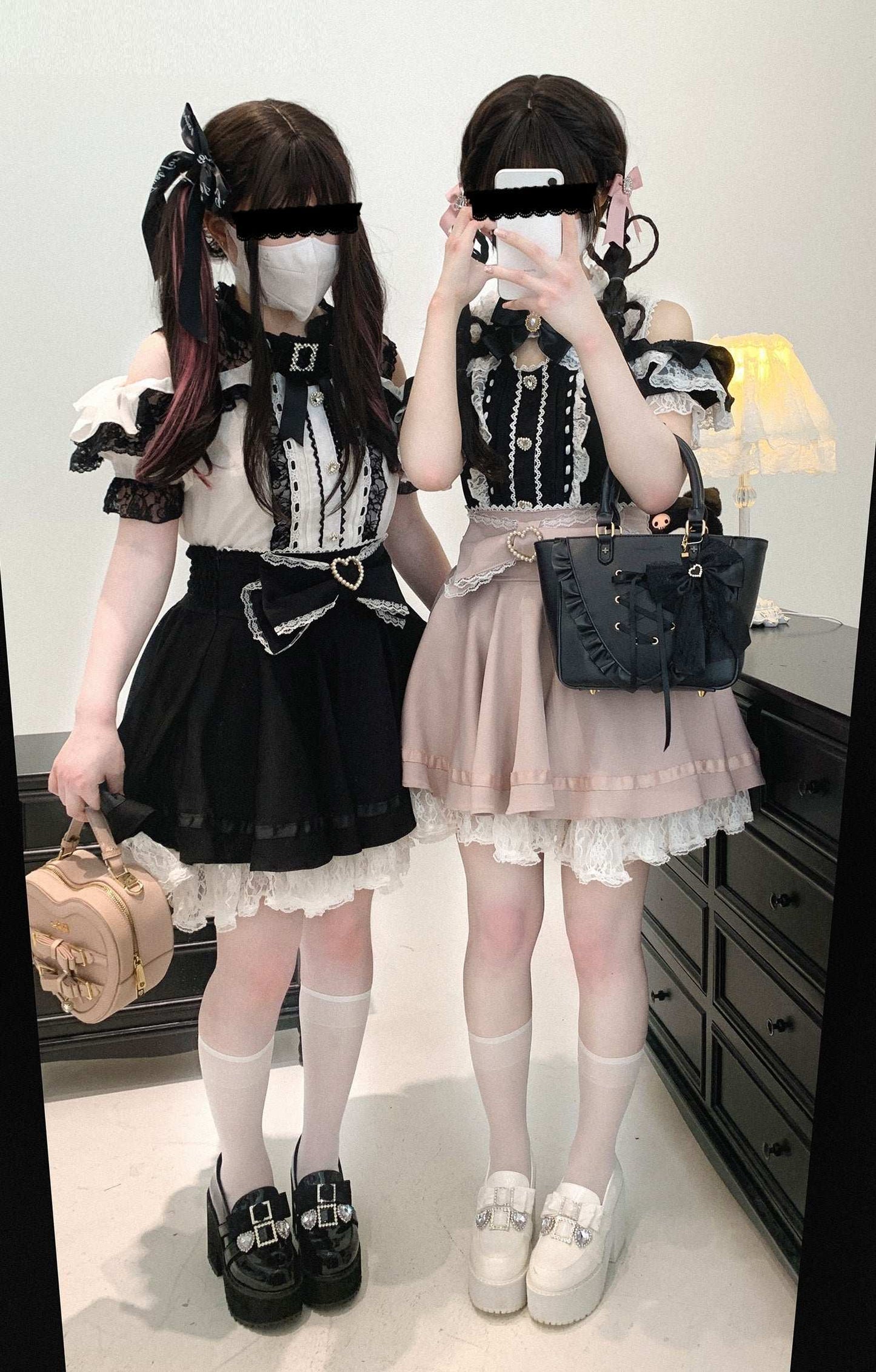 Two people in black and white outfits with skirts, standing in a room.