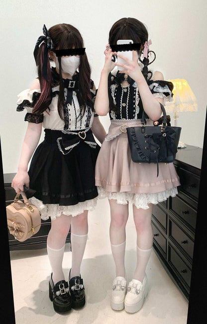 Two people in black and white outfits with skirts, standing in a room.