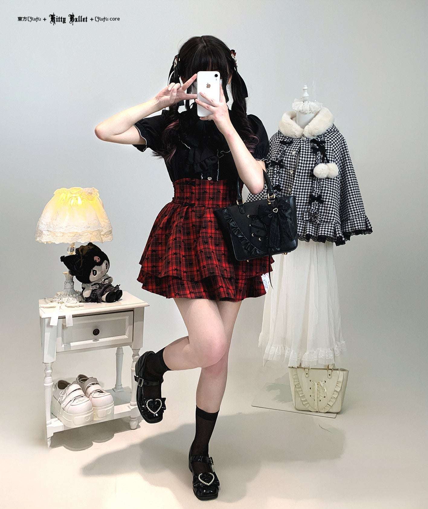 Person wearing a black top and red plaid skirt with a checkered coat and white shoes in a room setting.