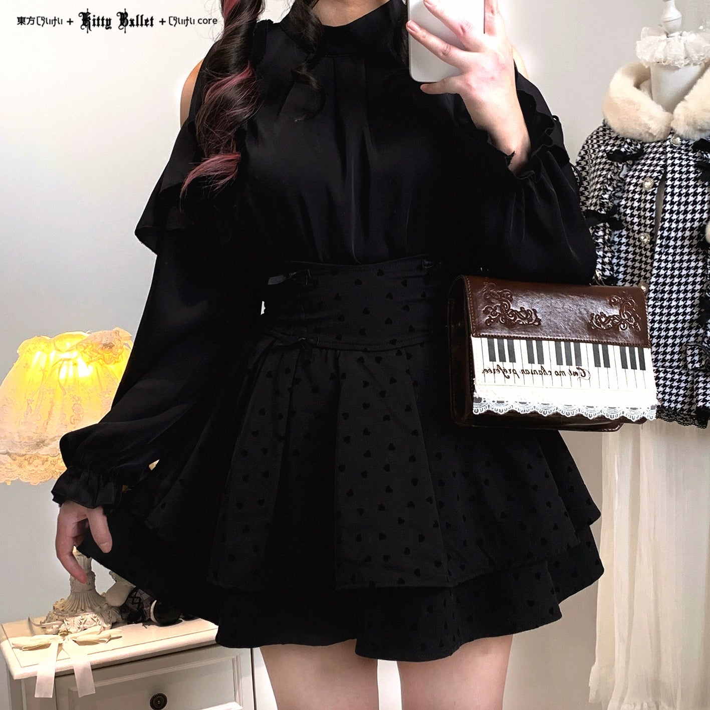 Person wearing a black dress with a polka dot pattern, holding a keyboard-shaped clutch.