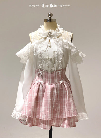 White blouse with ruffled sleeves and pink plaid skirt in jirai kei style on a mannequin against a plain background