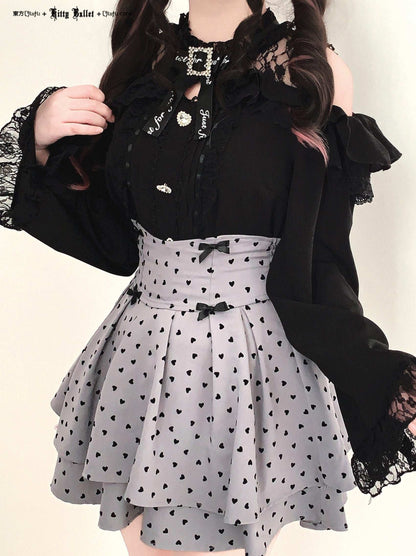 Person wearing a black top with lace details and a gray skirt in jirai kei style with black heart patterns.
