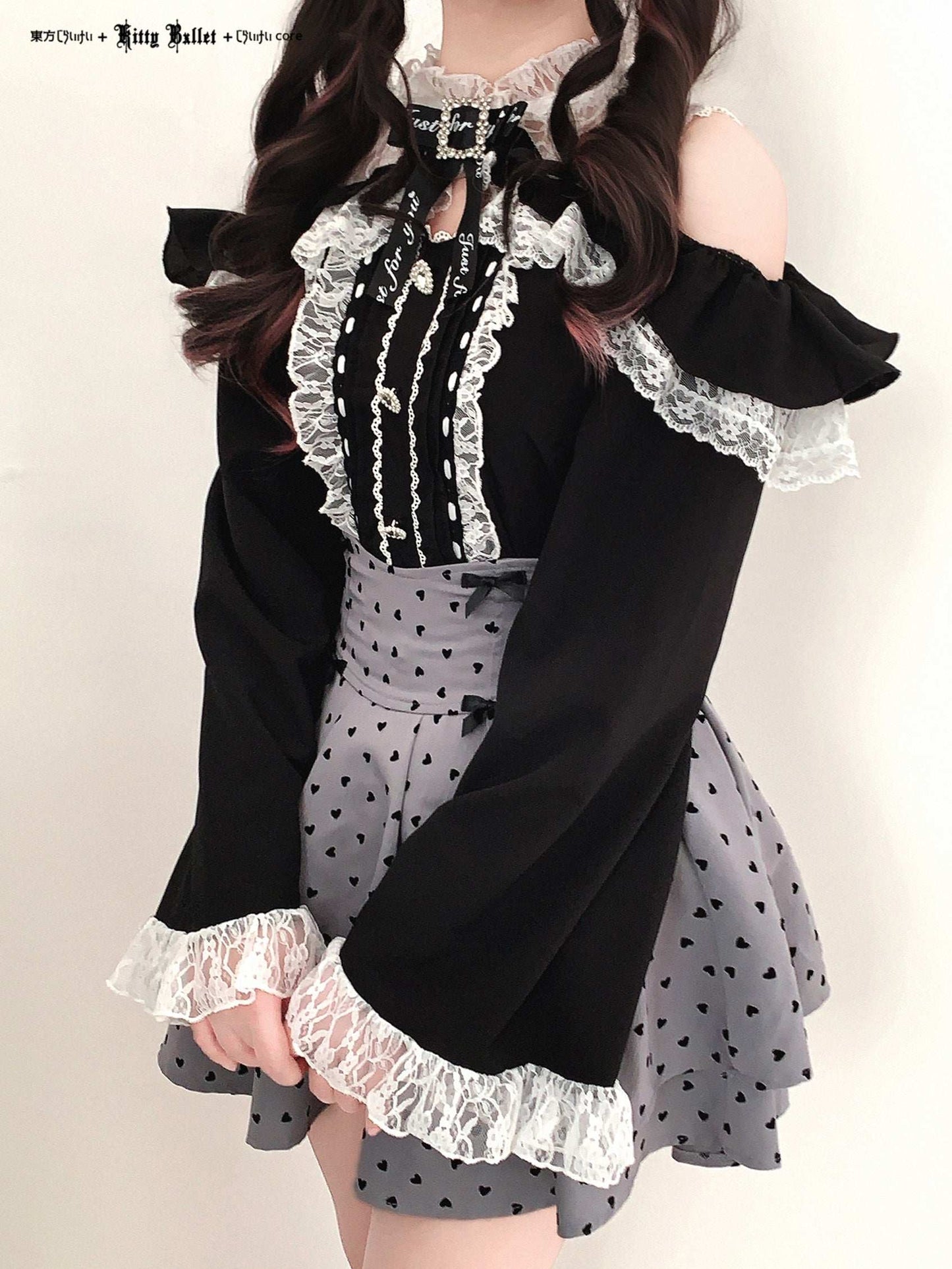 Black and white outfit with lace details in jirai kei style on a plain background