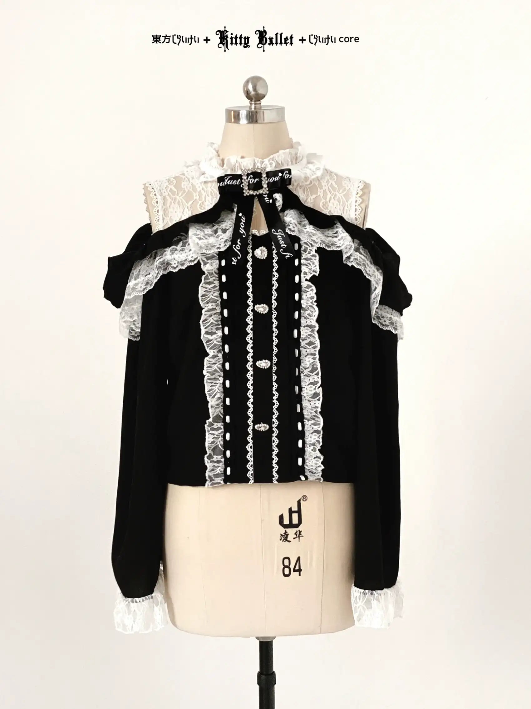 Black blouse with white lace details in jirai kei style on a mannequin against a white background