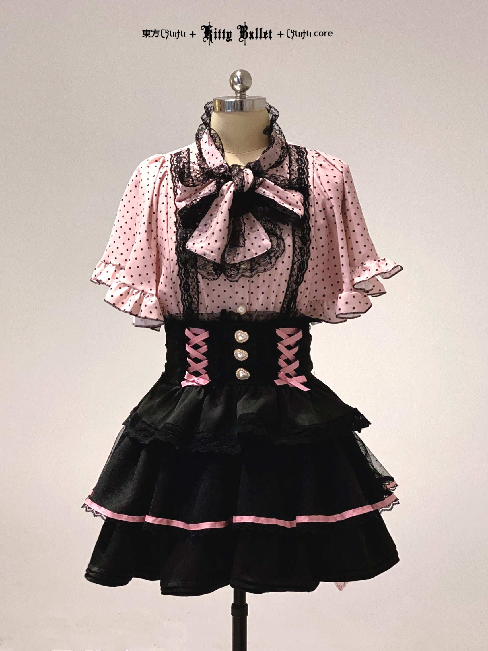 Black and pink jirai kei dress with a bow on a mannequin against a plain background