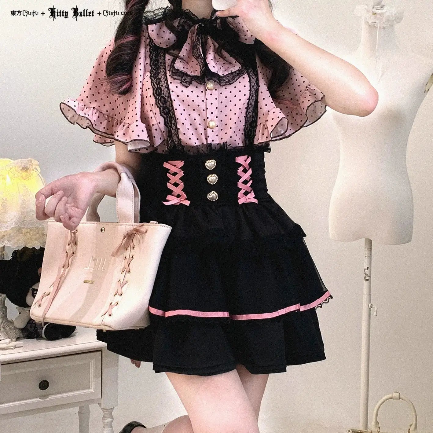 Person wearing a jirai kei black and pink outfit with a lace top and skirt, holding a beige handbag.