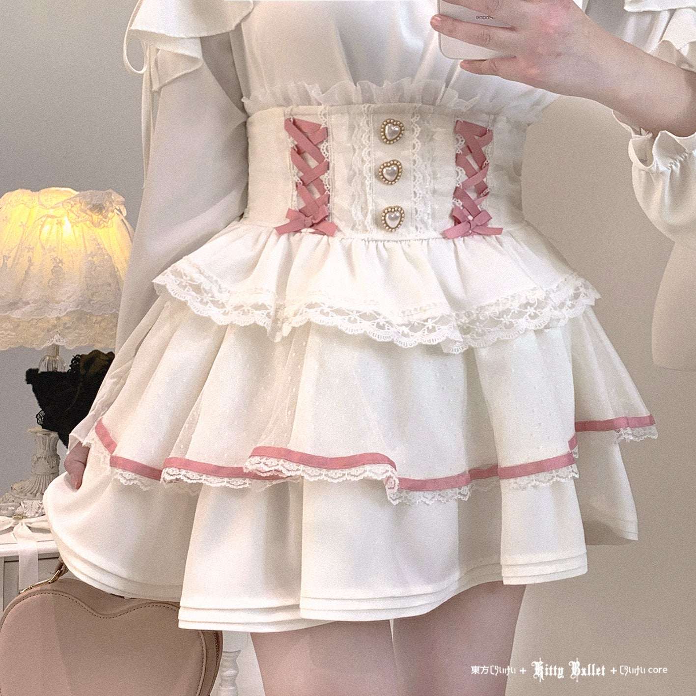 White dress with jirai kei pink accents and ruffles in a softly lit room.