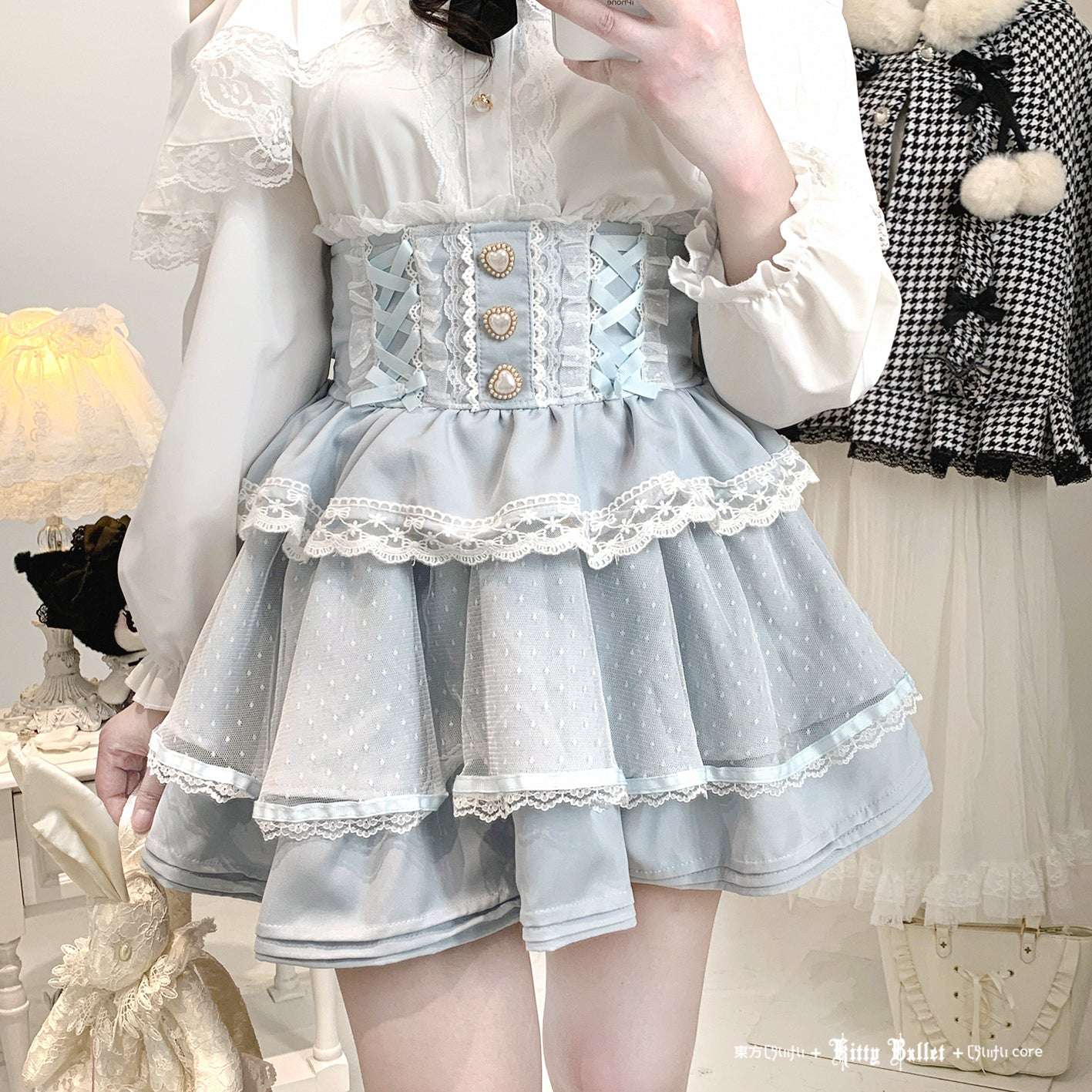 Person wearing a light jirai kei blue lace dress with a white shirt in a room setting.