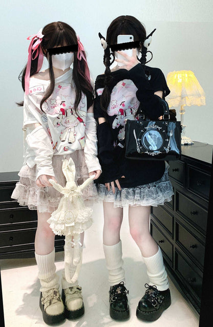 Two individuals in gothic Lolita fashion standing in a room with a lamp in the background.