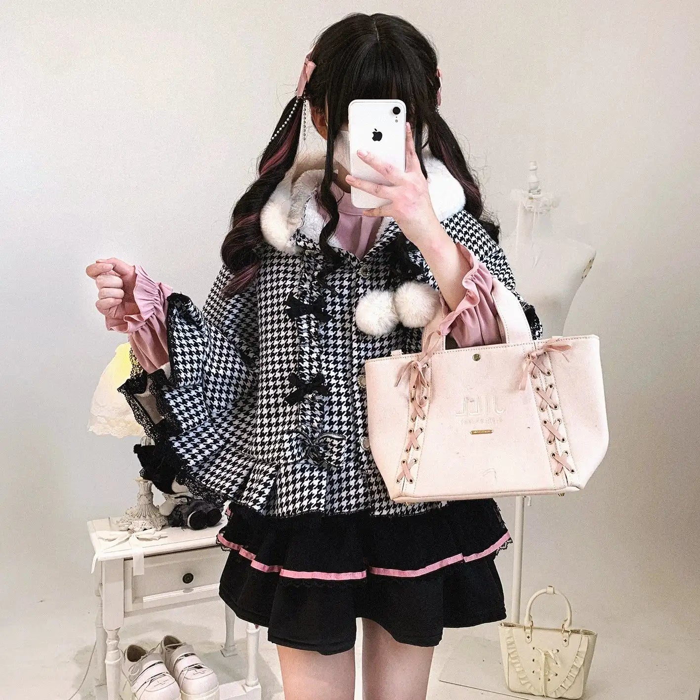 Person holding a pink handbag with decorative ribbons in a room setting.