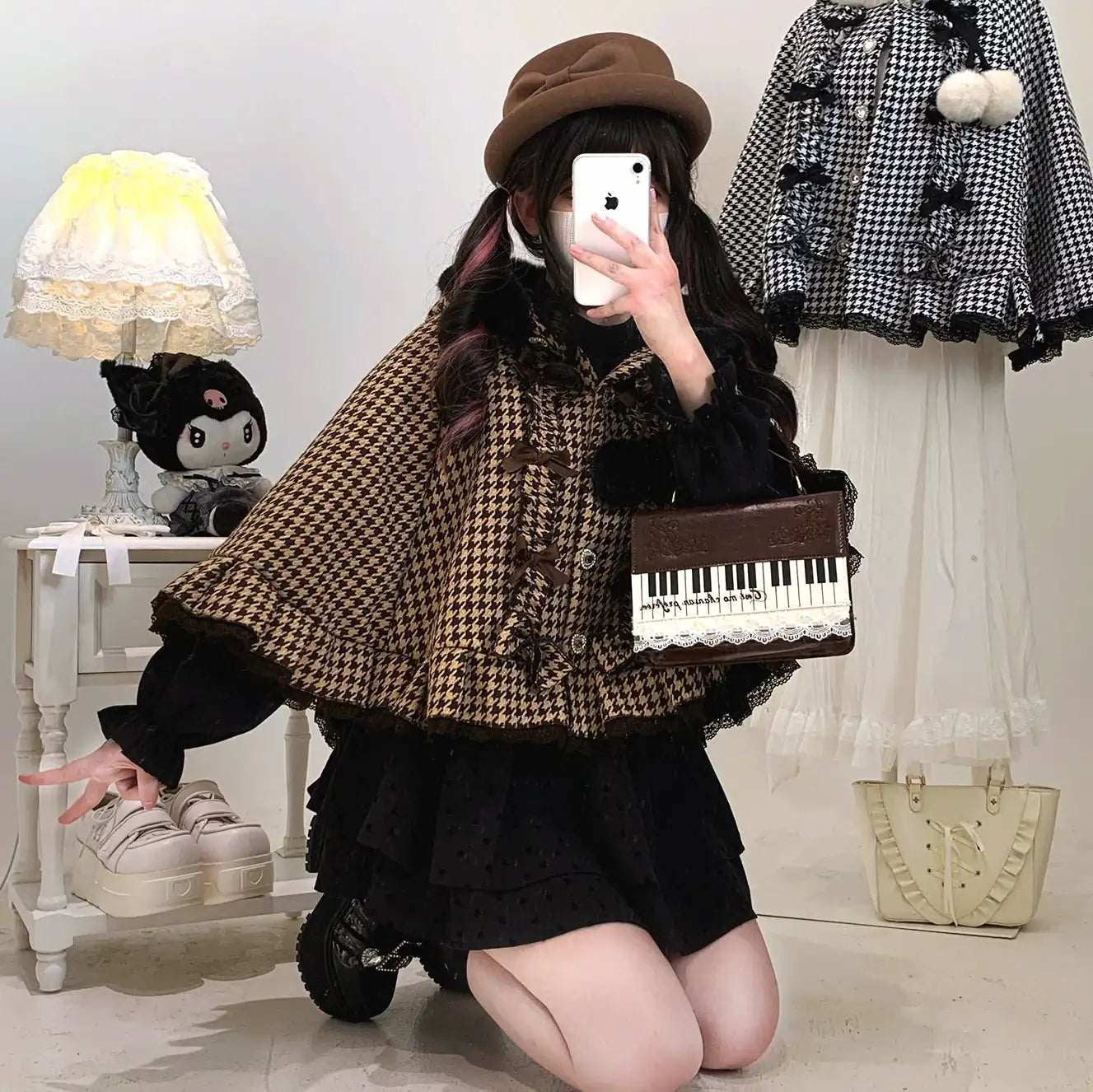 Person wearing a brown checkered coat and black skirt, holding a keyboard-themed bag, in a room with a lamp and doll.
