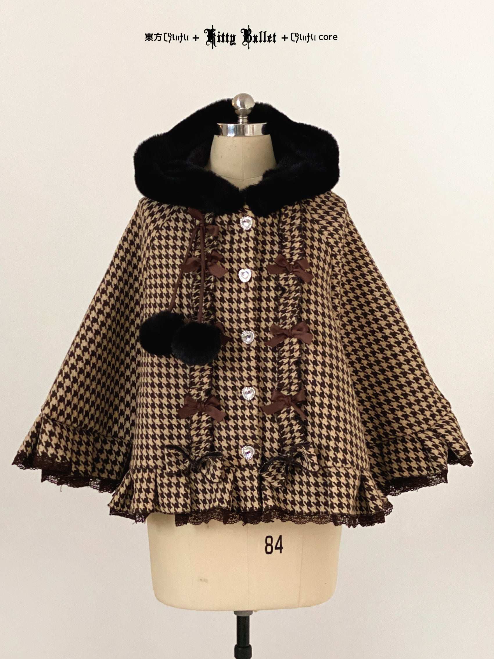 Houndstooth patterned cape with black fur trim on a mannequin against a plain background.