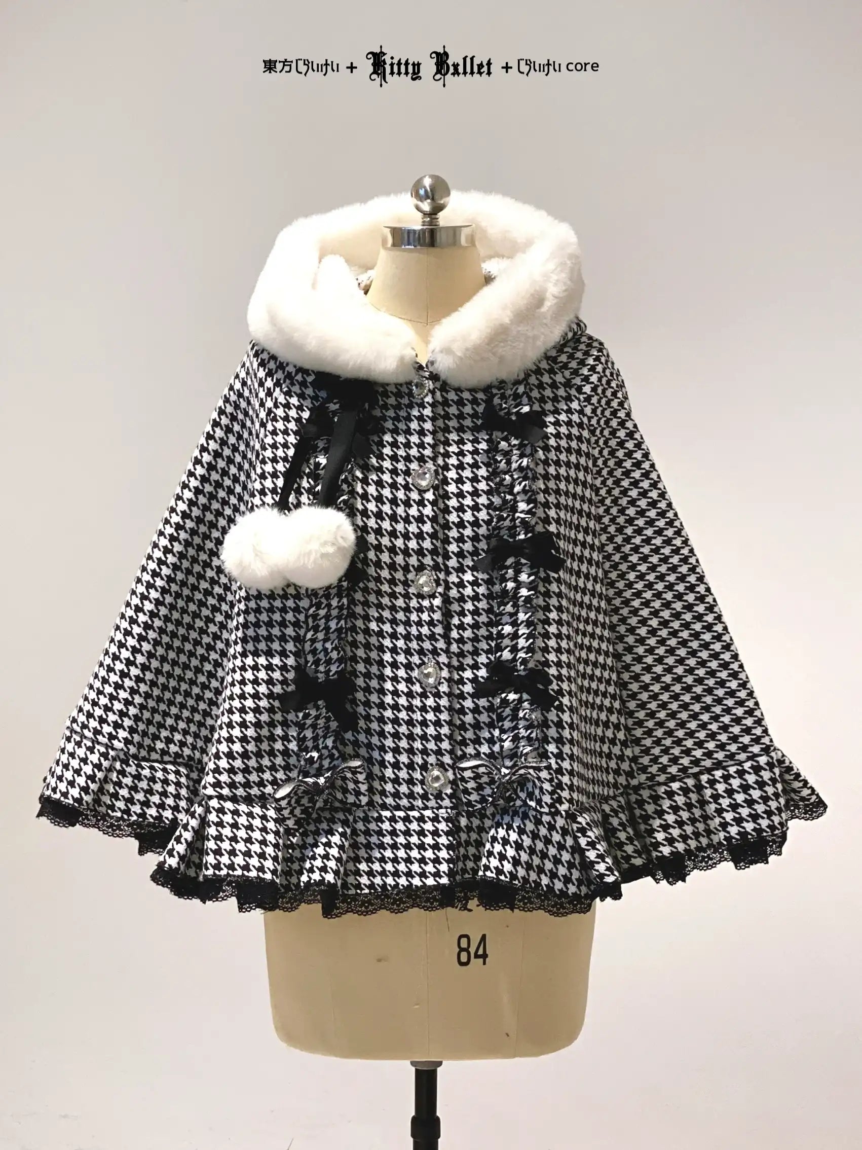 Black and white checkered poncho with fur trim on a mannequin against a plain background