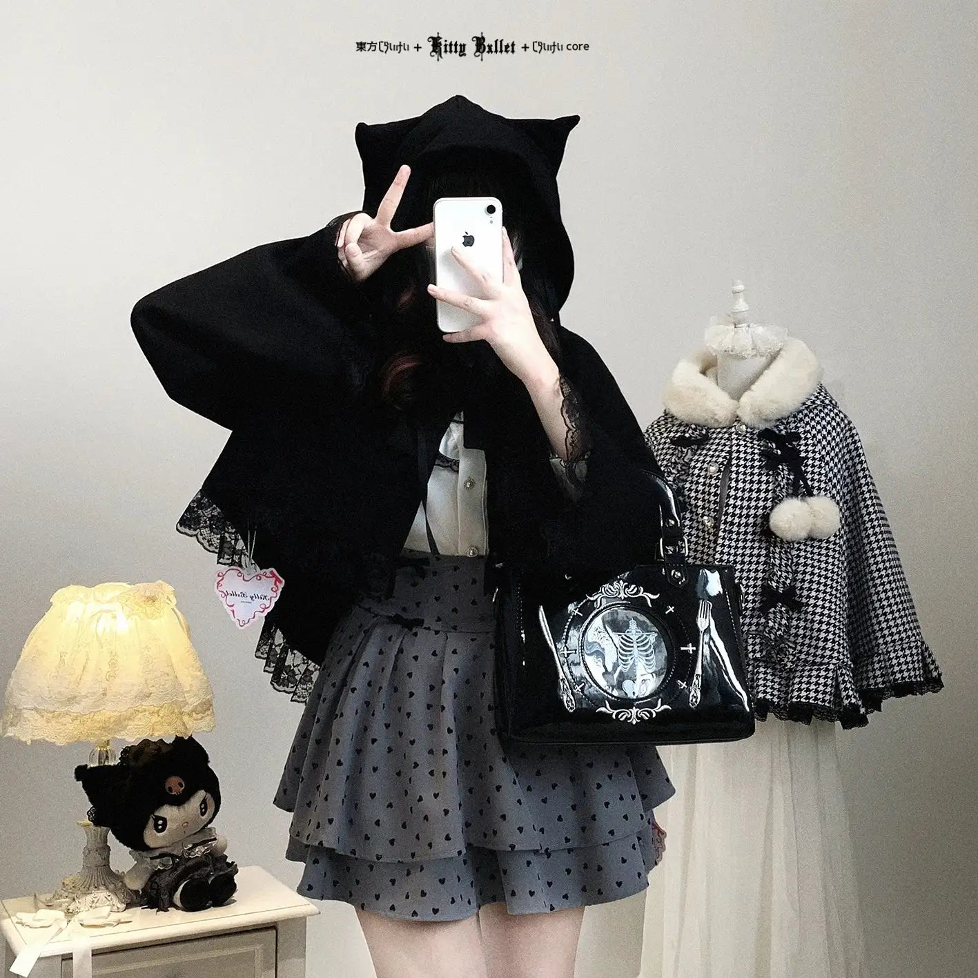 Person wearing a black hooded coat with a phone, surrounded by fashion items including a lamp and mannequin with a checkered coat.