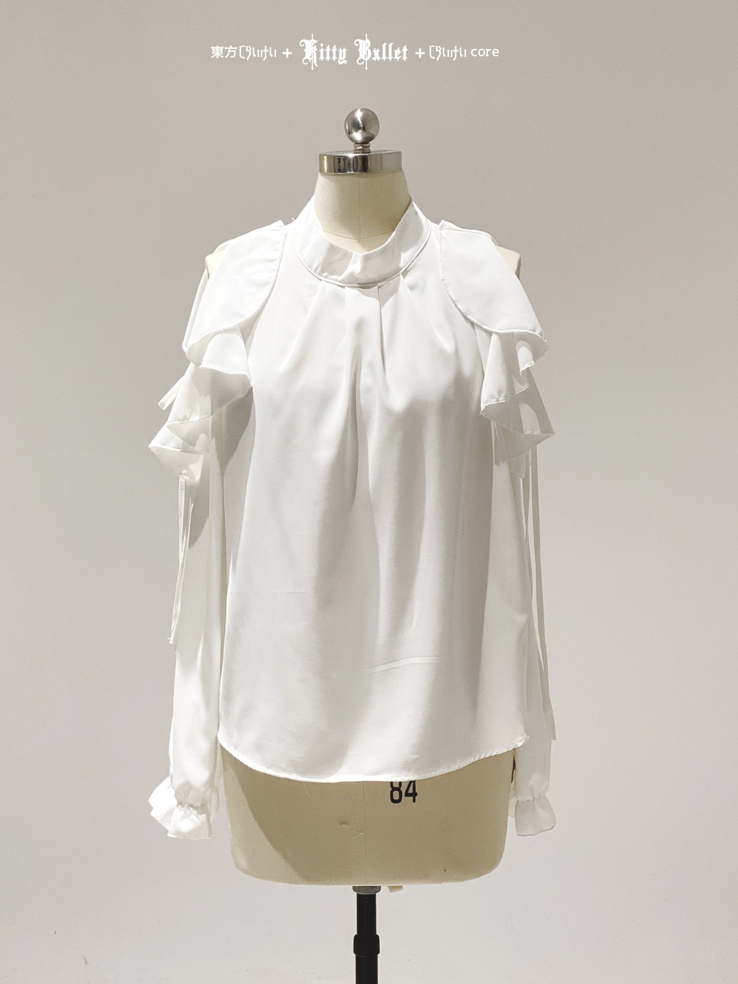 White blouse with ruffled details on a mannequin against a gray background